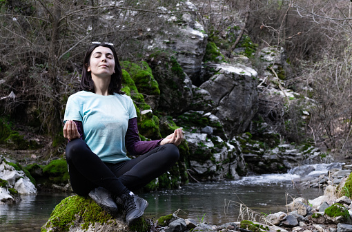 An image of a young woman doing yoga near the river