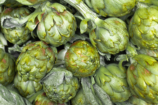 Close-up on a stack of artichokes on a market stall.