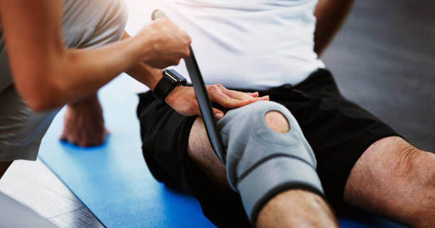 This will help quicken the healing process Shot of an unrecognizable female physiotherapist strapping a knee brace on a male patient knee brace stock pictures, royalty-free photos & images