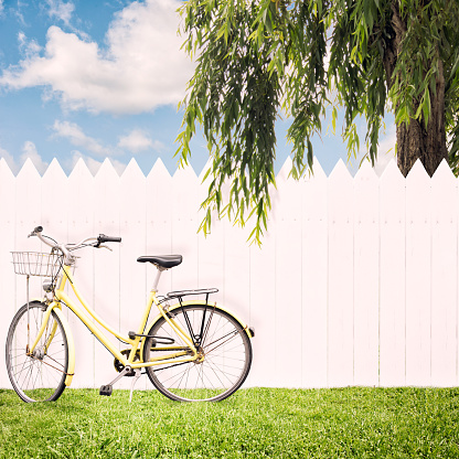 yellow bike in front of a white fence