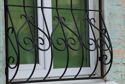 black iron grill with wrought rods on a glass window