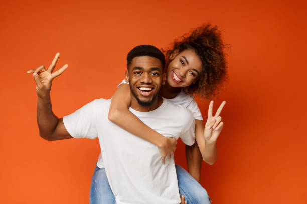 istock Young black couple piggyback ride, showing ok gesture 1143286271