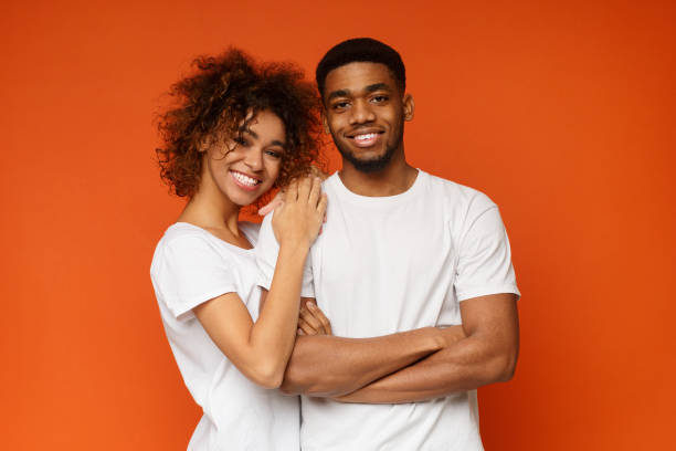 istock Young african-american couple posing on orange background 1143286273