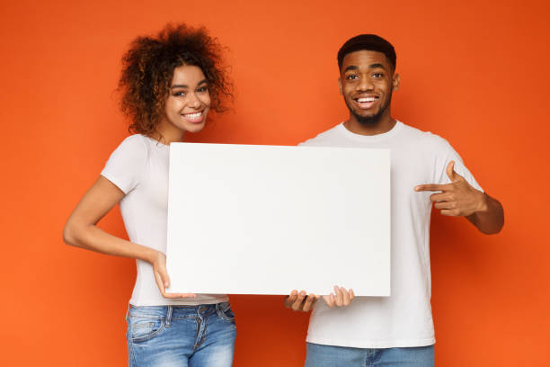 Young happy couple holding blank white board