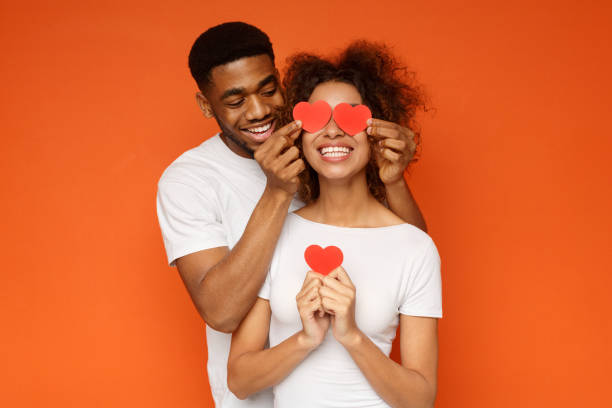 молодая пара, держащая красные любовные сердца над глазами - flirting humor valentines day love стоковые фото и изображения