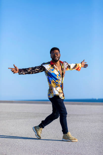 istock Front view of an african american man standing outdoors while arms raised in sunny day 1143287432