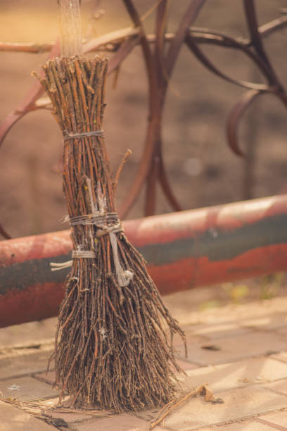 Old homemade broom made from the branches stands in the courtyard with sunlight