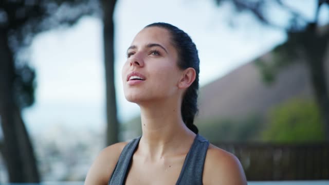 4k video footage of a beautiful young woman practising yoga outside