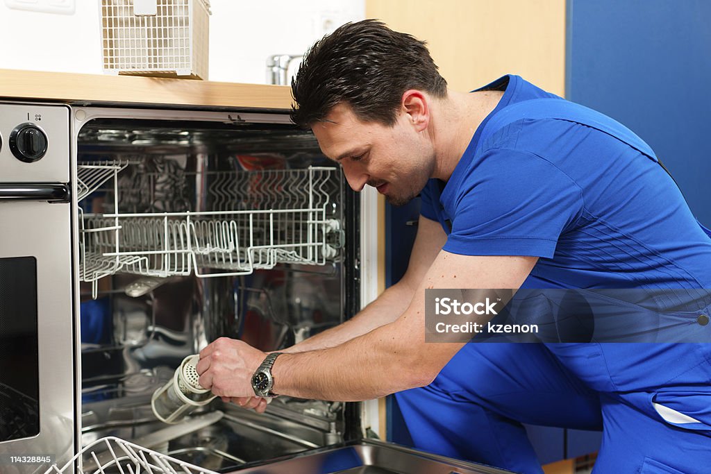 Technician repairing a dishwasher Technician or plumber repairing the dishwasher in a household Repairing Stock Photo