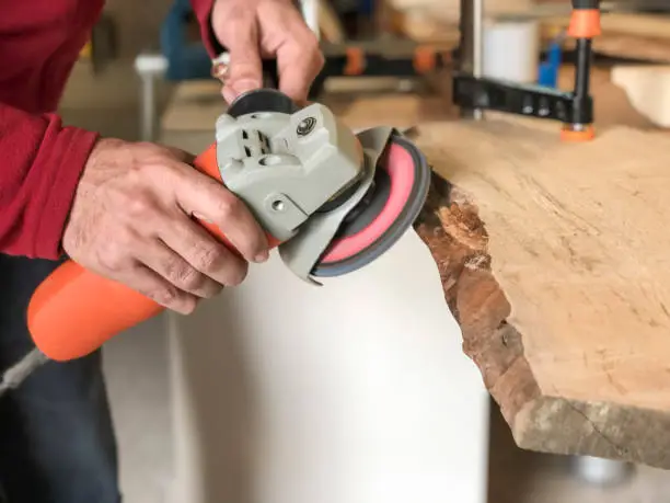 closeup hands of a carpenter working with emery wheel