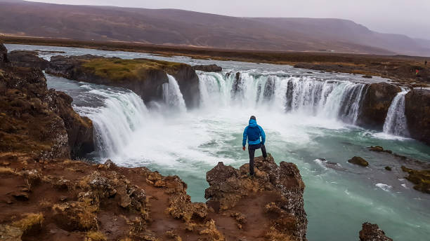 istock Iceland - Man standing in front of Stunning Godafoss 1143295865