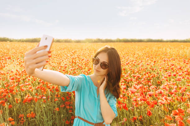 mujer tomando selfie en el campo de amapolas rojas. - poppy flower field red fotografías e imágenes de stock