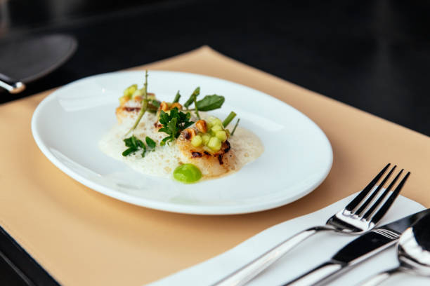 istock Molecular Creative Fine Dining: Hokkaido Scallop with green apple, hazelnut and shellfish veloute. Served in white plate on leather mat. 1143301095