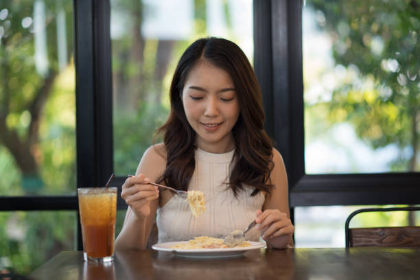 istock Young Asian woman eating spaghetti carbonara 1143307022