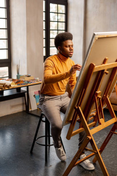 istock Nice talented man sitting in front of his painting 1143307835