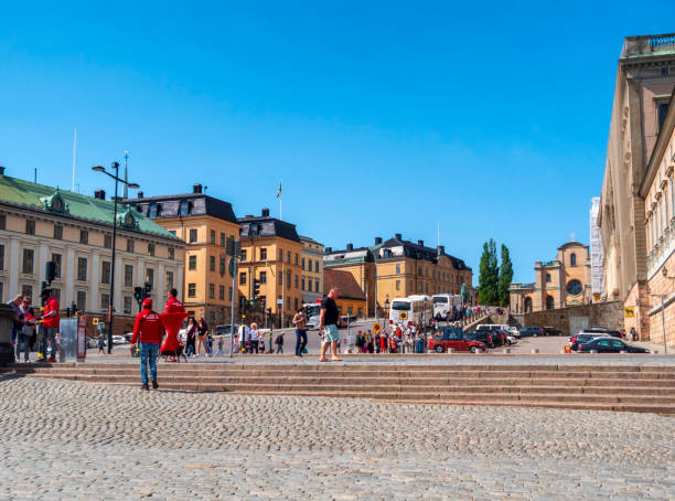 туристы в slottsbacken с королевским дворцом справа, стокгольм - stadsholmen стоковые фото и изображения