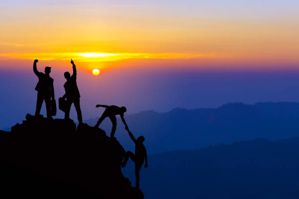 teamwork freundschaftswandern helfen sich gegenseitig treuhand-silhouette in den bergen, sonnenaufgang. teamwork von vier männer-wanderer, die sich gegenseitig auf dem bergsteigerteam schöne sonnenaufgangslandschaft helfen - ideas concepts power sunrise stock-fotos und bilder