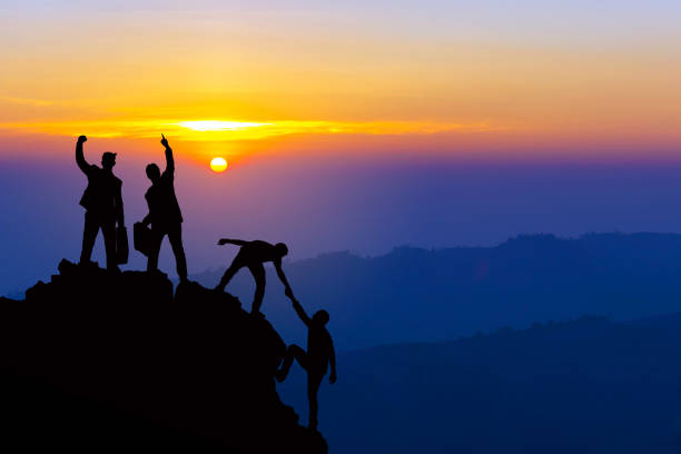 le escursioni di amicizia di lavoro di squadra si aiutano a vicenda a fidarsi della silhouette di assistenza in montagna, all'alba. lavoro di squadra di quattro escursionisti uomini che si aiutano a vicenda in cima alla squadra di arrampicata in montagna b - conquering adversity mountain hiking mountain climbing foto e immagini stock