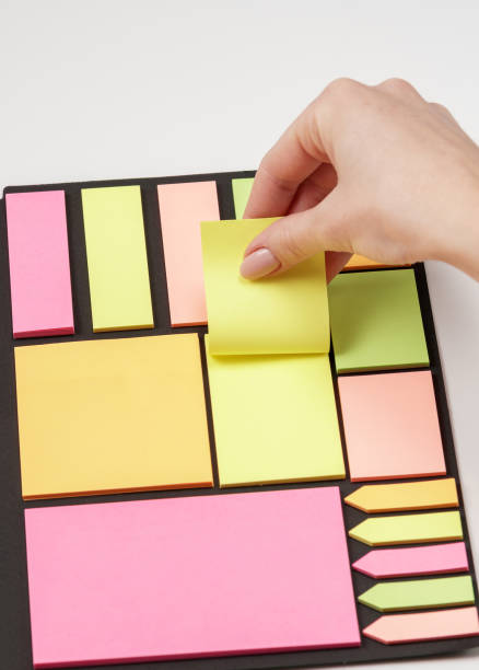 istock Blank note paper set of different colours forms and sizes. Sticky notes collection on black background. Female hand tear off paper note 1143326615