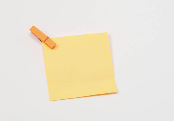 istock Orange paper notes fastened with a wooden clothespin on a white background. 1143326626