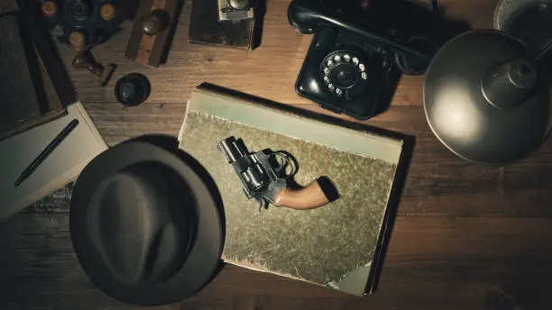 Noir 1950s style detective vintage desktop with revolver, fedora hat and telephone, flat lay