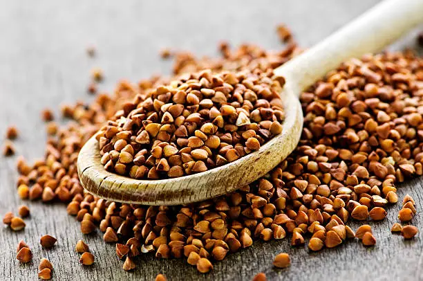 Photo of Wooden spoon filled with buckwheat grain