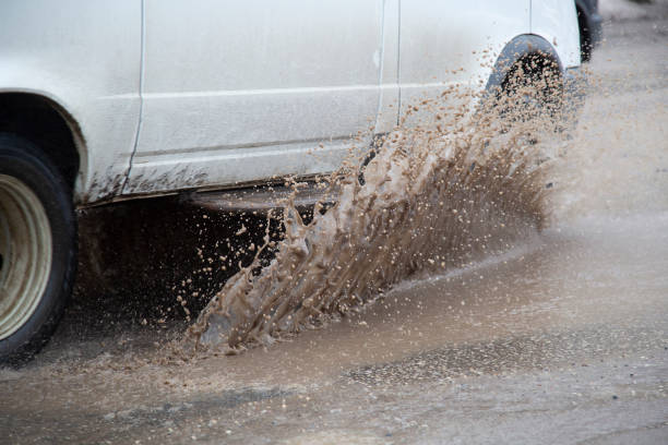 istock Moving car sprays puddle when heavy rain drops on concrete. 1143332739