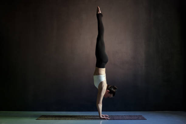 istock woman practicing yoga, Adho Mukha Vrksasana exercise, Downward facing Tree pose 1143332853