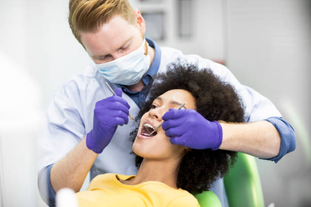 istock Dentist using an excavator sickle probe and a mouth mirror to perform a dental check-up 1143334324