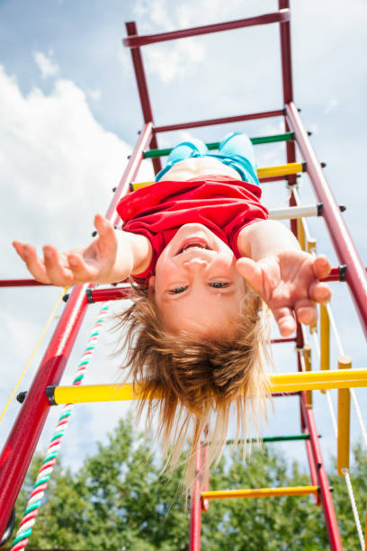 little girl hanging from a jungle gym playing in a summer garden - child jungle gym playground laughing imagens e fotografias de stock