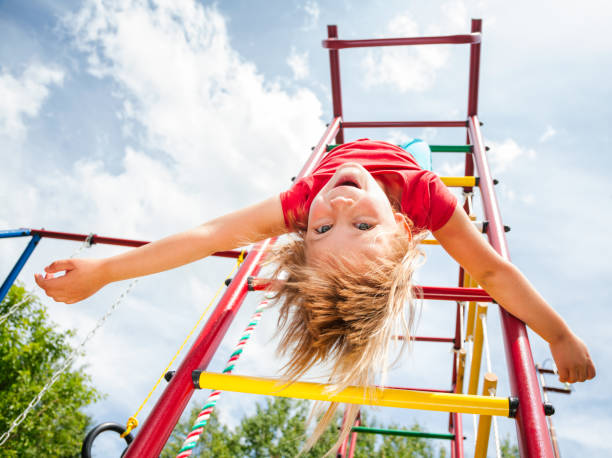 little girl hanging from a jungle gym playing in a summer garden - child jungle gym playground laughing imagens e fotografias de stock