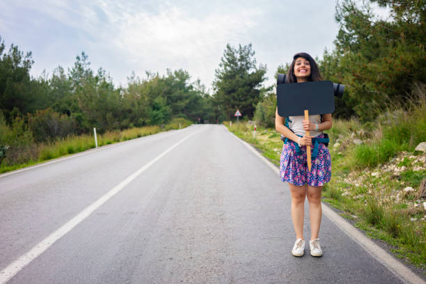 Woman hitchhiking with blank sign for your text.