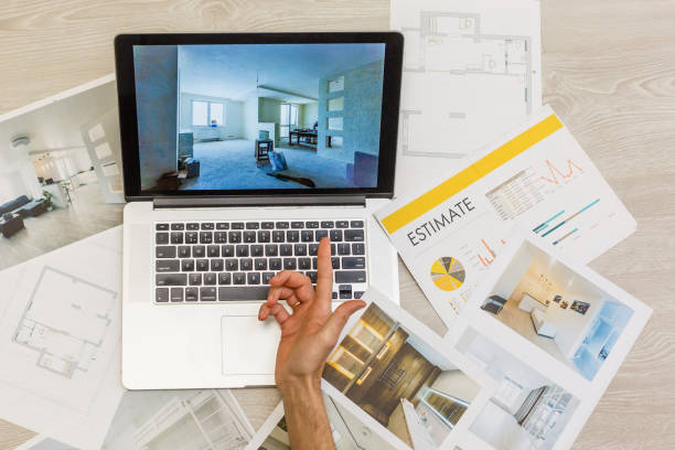 istock Decorator's hands with ruler on project drawings. Laptop, color swatches and tools on work table 1143338683