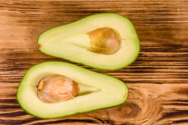 istock Halved avocado fruit on a wooden table. Top view 1143339572
