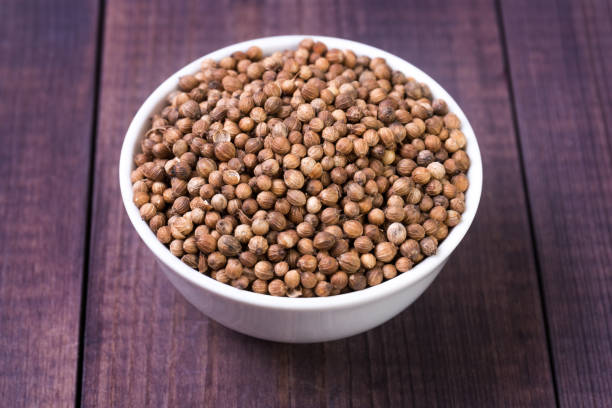 istock Coriander seeds in a white bowl on a wooden background 1143339867