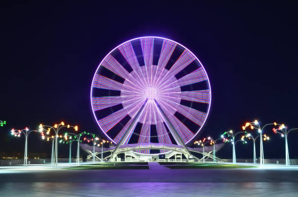 une grande roue à bakou sur le rivage de la mer caspienne, la nuit avec des lumières - blurred motion amusement park spinning lighting equipment photos et images de collection