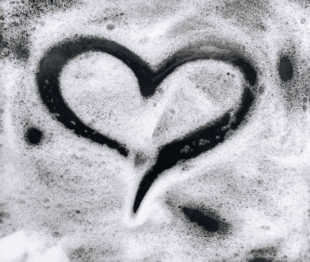 Heart shape on soap foam on black background. stock photo