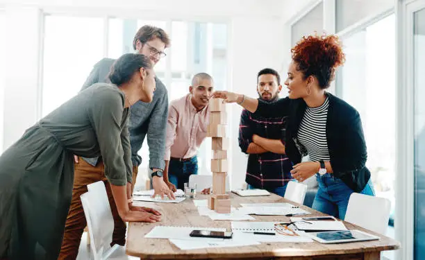 Shot of a group of young businesspeople having a meeting with building blocks in a modern office