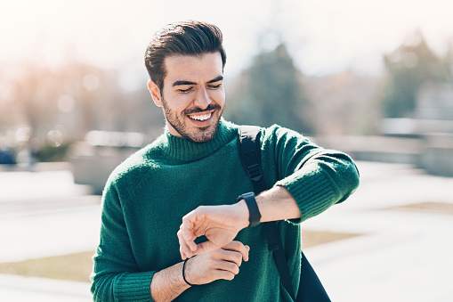 Smiling man with smart watch walking outdoors in the city