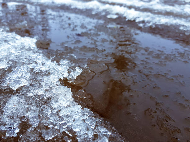 istock Beautiful puddles with ice crust, snow and reflection in winter or spring 1143346584