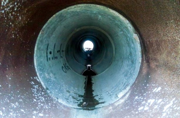 tunnel zur entwässerung von regenwasser unter der straße. blick durch die pfeife - when it rains it pours stock-fotos und bilder
