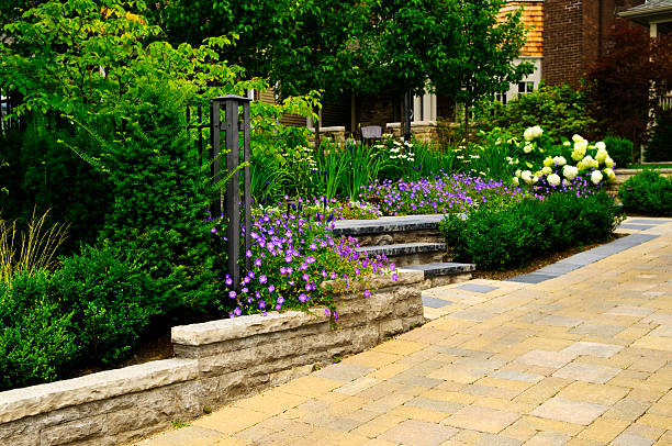 Landscaped garden and stone paved driveway Natural stone landscaping in front of a house with lush green garden interlocking concrete pavement stock pictures, royalty-free photos & images