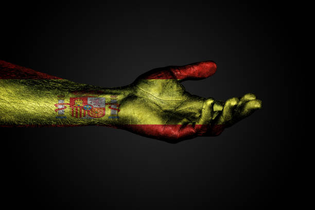 istock Outstretched hand with a drawn Spain flag, a sign of help or a request, on a dark background. 1143351425