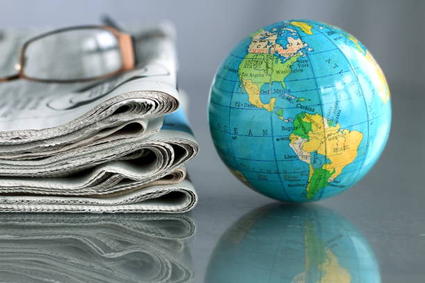 newspaper with globe printed newspaper on a table with glasses white background and globe world news stock pictures, royalty-free photos & images