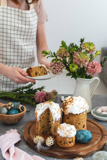 istock Easter table female serving cake, ranunculus flowers, easter cake, milk bottle, coloured eggs, quail eggs, willow banch, vertical 1143363085