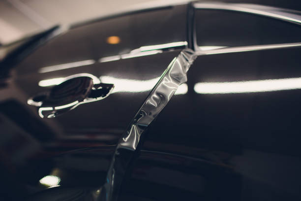 istock Worker hands installs car paint protection film 1143373369