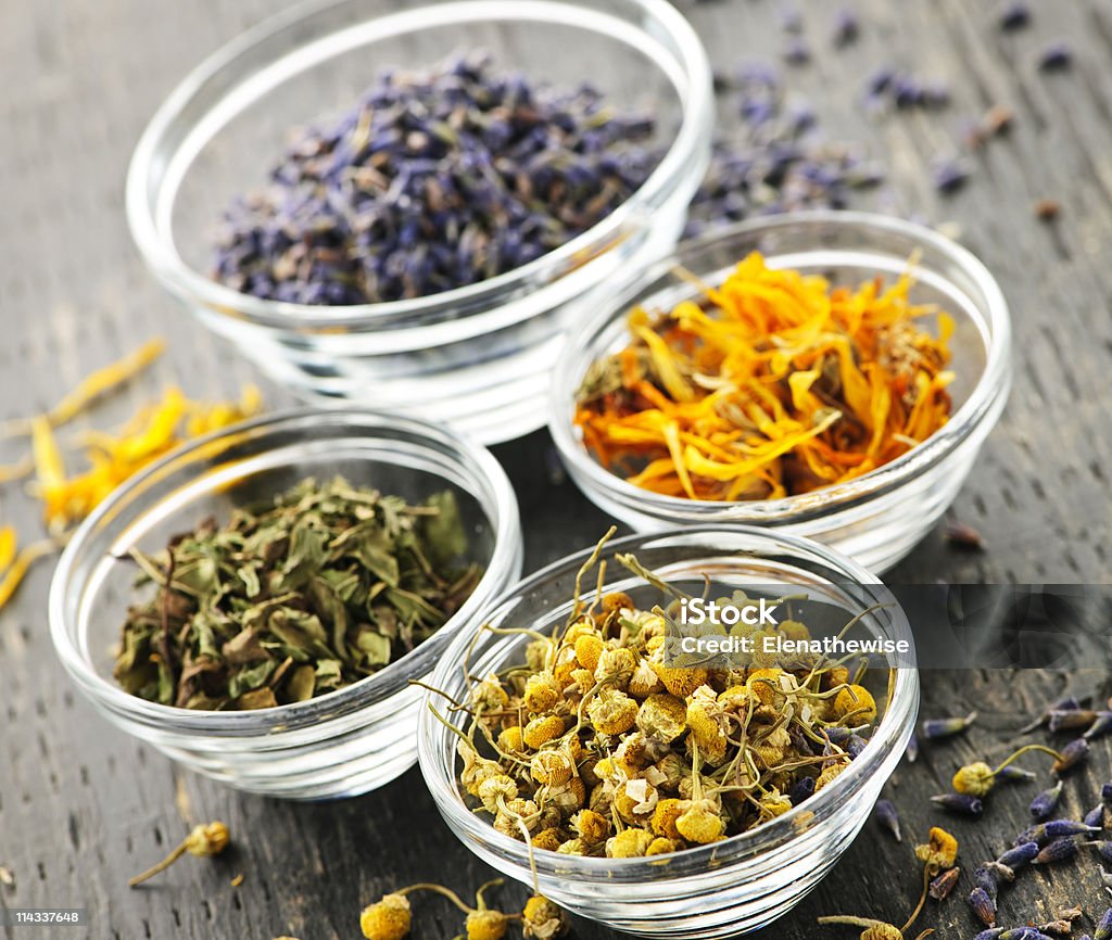 Four different kinds of dried medical herbs in glass bowls Assortment of dry medicinal herbs in glass bowls Dried Plant Stock Photo