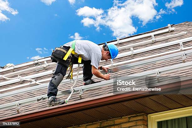 Uomo Che Lavora Sul Tetto Linstallazione Di Rails Per Pannelli Solari - Fotografie stock e altre immagini di Costruttore di tetti