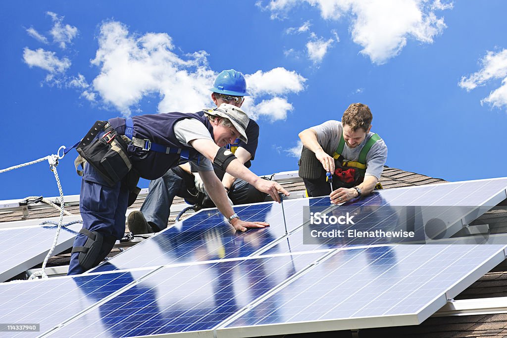 Solar panel installation Workers installing alternative energy photovoltaic solar panels on roof Solar Panel Stock Photo