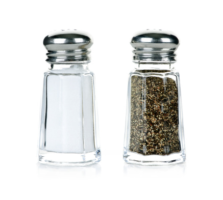 Pepper shaker with pile of ground black pepper isolated on white background.